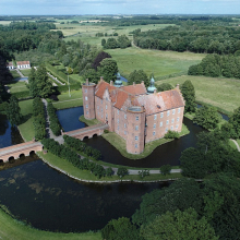 Gammel Estrup ligger som mange ældre herregårde lavt. Mod syd er der dobbelte voldgrave og mod nord løber Alling Å parallelt med voldgraven. Denne placering af hovedbygningen har ydet god beskyttelse mod eventuelle angreb. Foto: Det Flyvende Kamera.